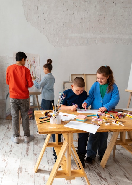 Foto gratuita niños de tiro completo pintando en la escuela