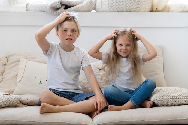 Niños de tiro completo con piojos en el sofá