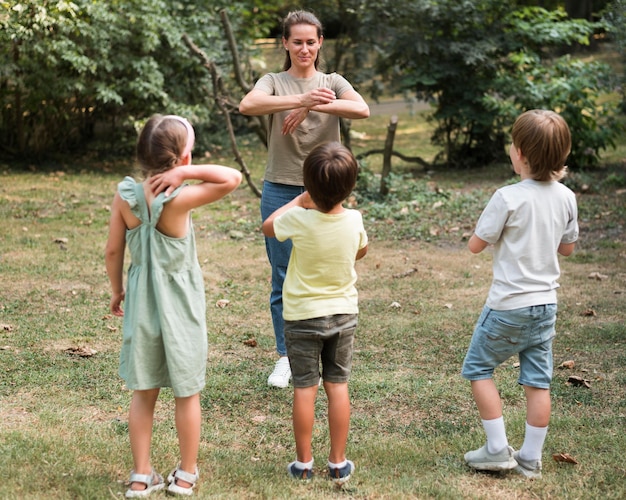 Niños de tiro completo y profesor jugando al aire libre