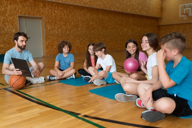 Niños de tiro completo y profesor sentado