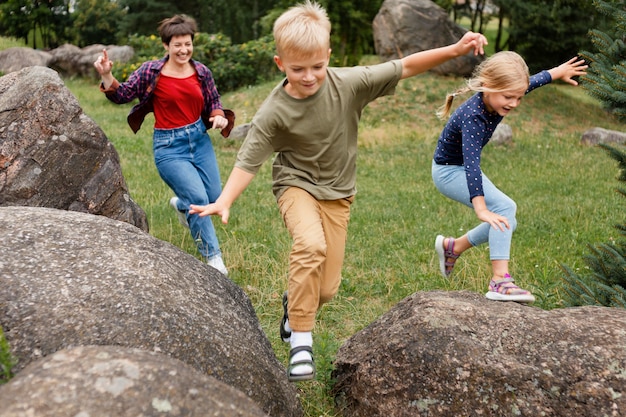 Niños de tiro completo saltando sobre rocas