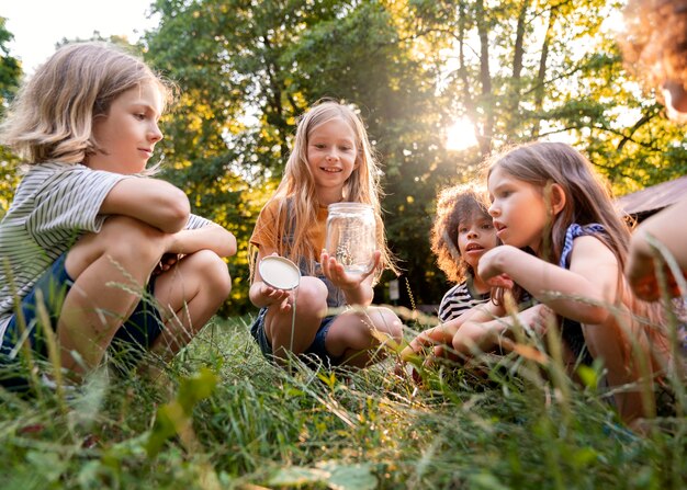 Niños de tiro completo sentados en el césped