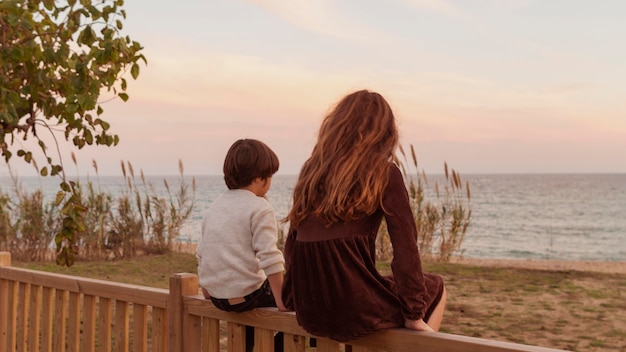 Niños de tiro completo sentados juntos en la valla