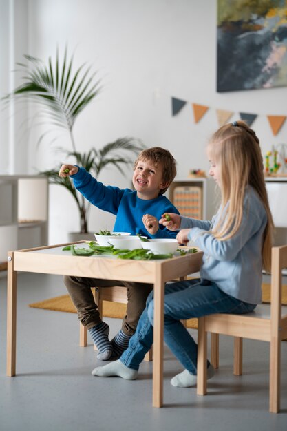 Niños de tiro completo sentados en la mesa