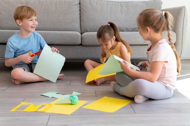 Niños de tiro completo trabajando con papel.