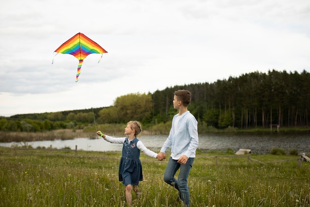 Niños de tiro completo volando una cometa afuera