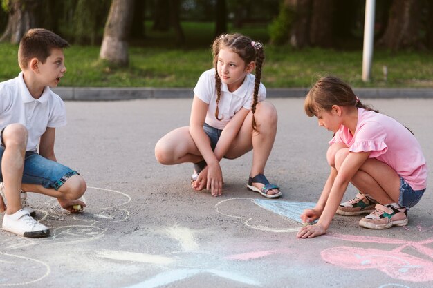 Niños de tiro largo dibujando con tiza