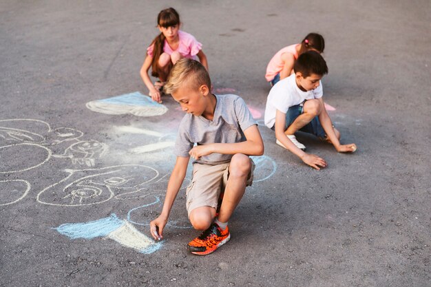 Niños de tiro largo haciendo dibujo con tiza