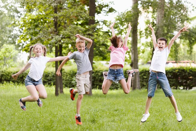 Niños de tiro largo saltando juntos