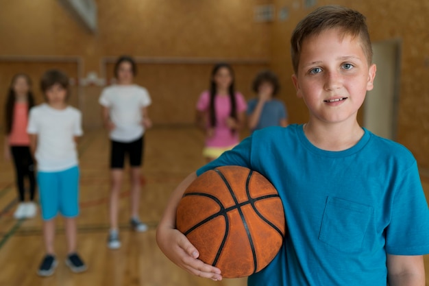 Niños de tiro medio con baloncesto en el gimnasio