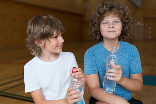 Niños de tiro medio con botellas de agua