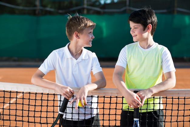 Niños de tiro medio en el campo de tenis.