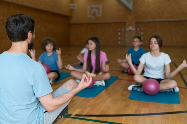 Niños de tiro medio en colchonetas de yoga en el gimnasio
