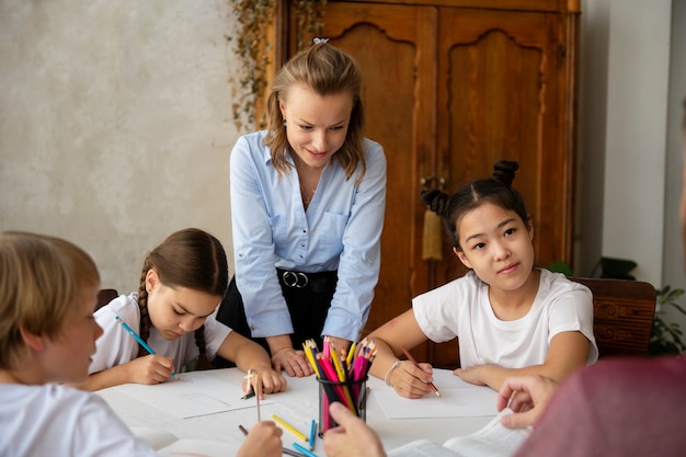 Niños de tiro medio dibujando en la mesa