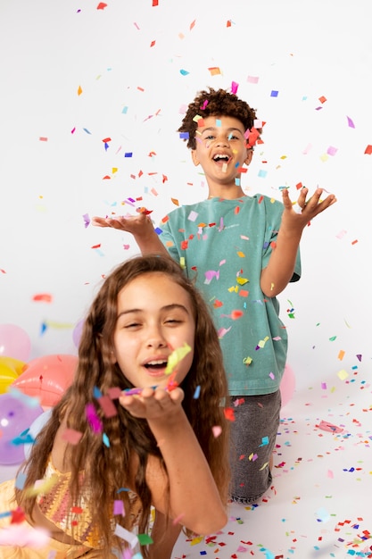 Foto gratuita niños de tiro medio divirtiéndose con confeti.