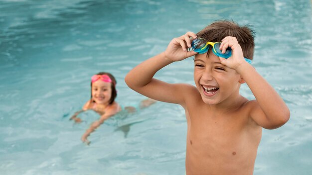 Niños de tiro medio divirtiéndose en la piscina