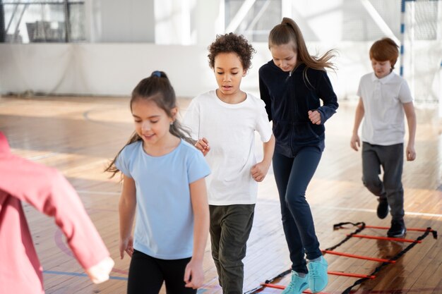 Niños de tiro medio entrenando juntos en el gimnasio