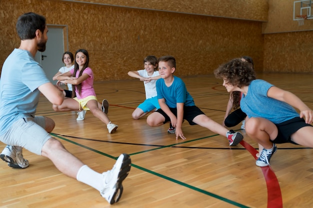 Niños de tiro medio haciendo ejercicio en el gimnasio de la escuela