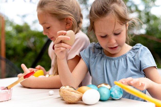 Niños de tiro medio con huevos pintados