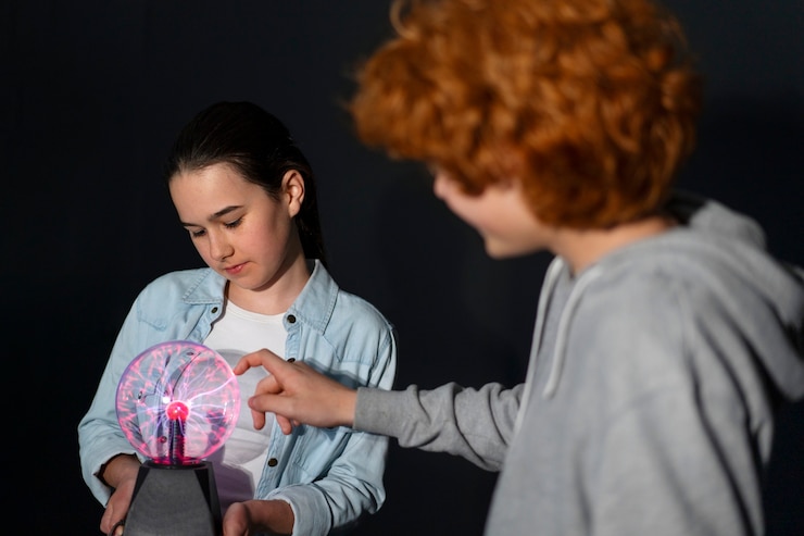Foto gratuito niños de tiro medio interactuando con una bola de plasma