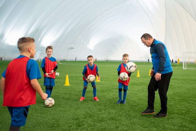 Niños de tiro medio jugando al fútbol