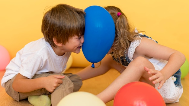 Niños de tiro medio jugando con globo.