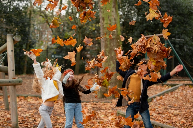 Niños de tiro medio jugando con hojas.