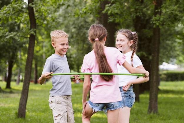 Niños de tiro medio jugando con hula hoop