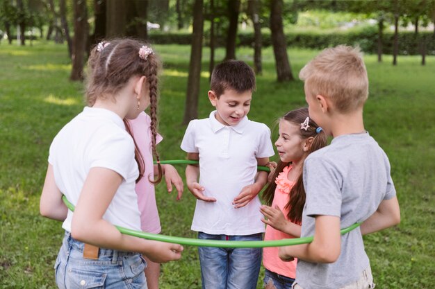 Niños de tiro medio jugando con hula hoop