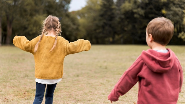 Foto gratuita niños de tiro medio jugando en la naturaleza.