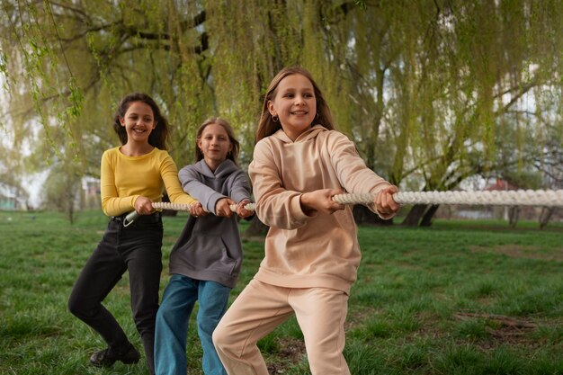 Niños de tiro medio jugando tira y afloja en el parque