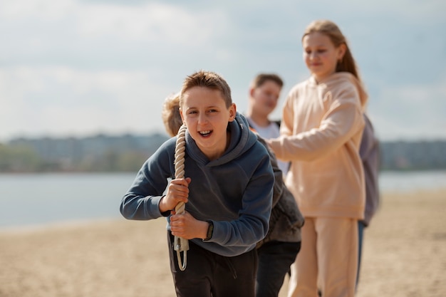 Foto gratuita niños de tiro medio jugando tira y afloja en la playa