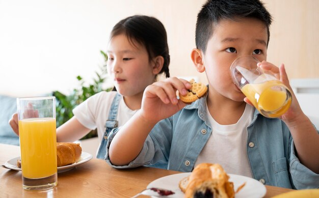 Niños de tiro medio con jugo de naranja