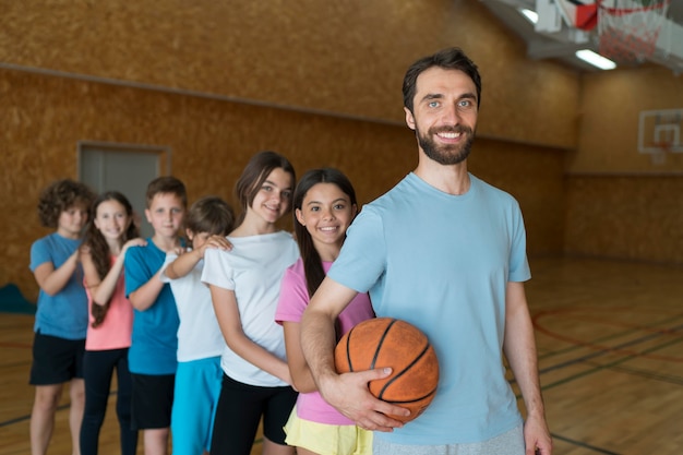 Niños de tiro medio y maestro con baloncesto