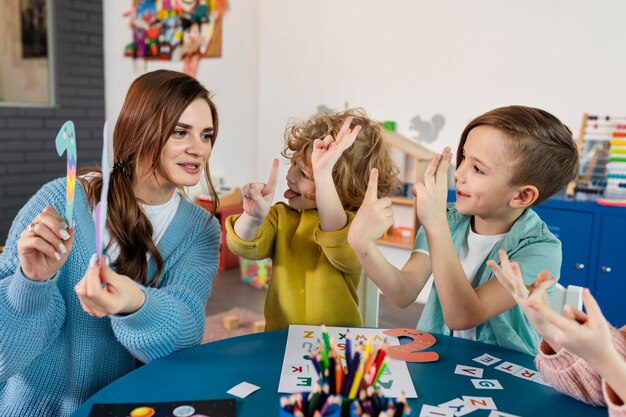 Niños de tiro medio y maestro en la mesa.