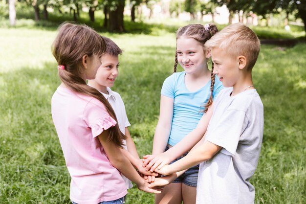 Niños de tiro medio con las manos juntas.