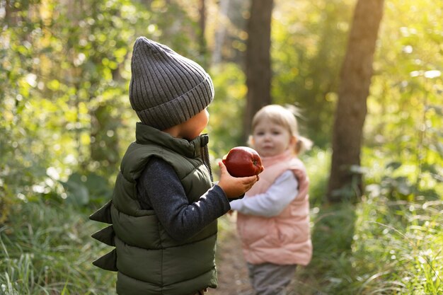 Niños de tiro medio con manzana en la naturaleza.