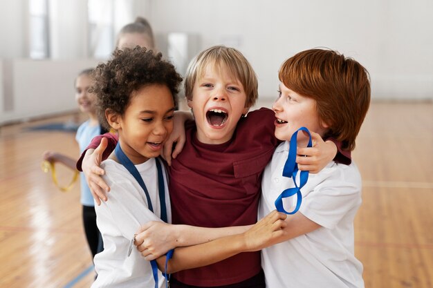 Niños de tiro medio con medallas abrazándose.