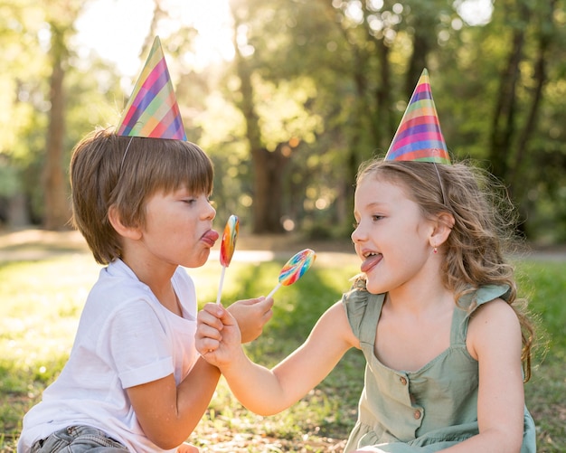 Niños de tiro medio con piruletas