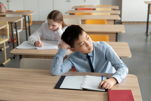 Niños de tiro medio sentados en escritorios