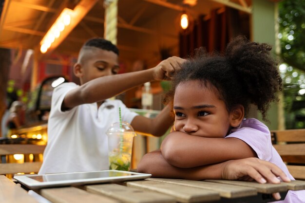 Niños de tiro medio sentados a la mesa con dispositivo