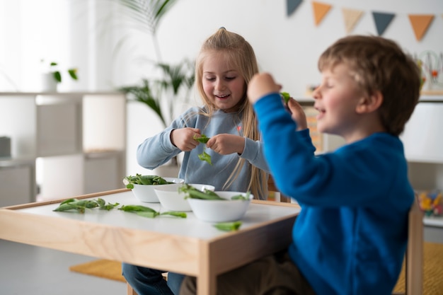 Foto gratuita niños de tiro medio sentados en la mesa