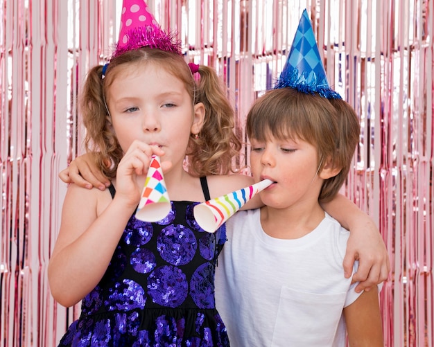 Niños de tiro medio con silbatos de fiesta