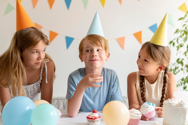 Niños de tiro medio con sombreros de fiesta