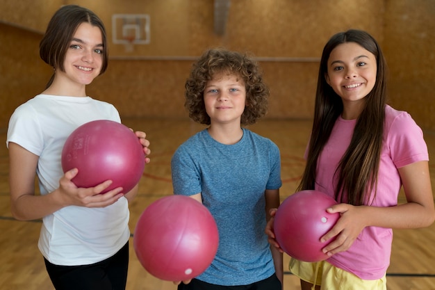 Niños de tiro medio sosteniendo bolas