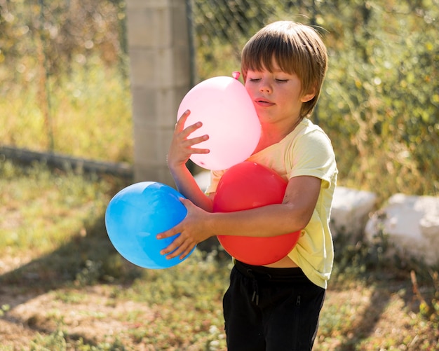 Niños de tiro medio sosteniendo globos