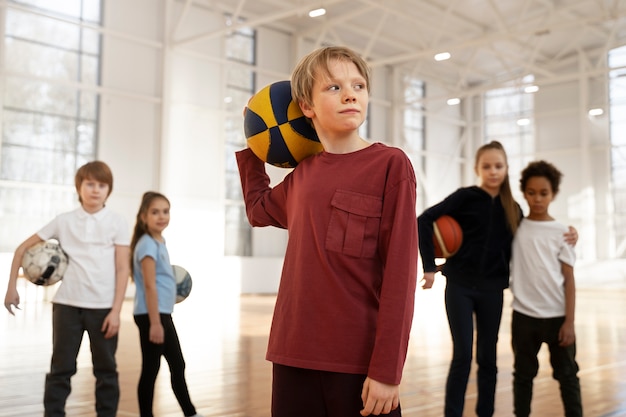 Niños de tiro medio sosteniendo pelotas