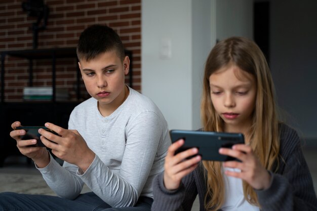 Niños de tiro medio con teléfonos inteligentes.