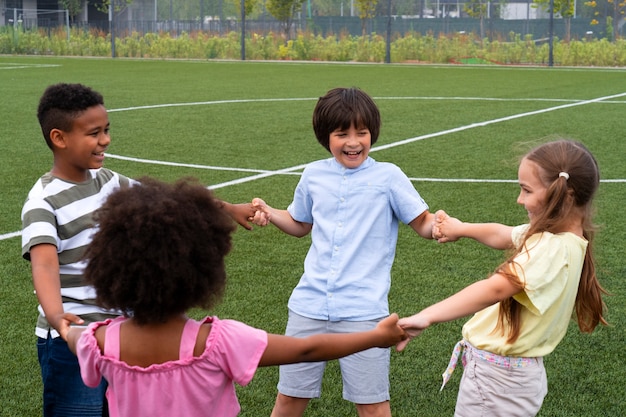 Niños de tiro medio tomados de la mano