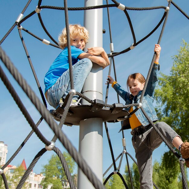 Niños de tiro medio trepando cuerda juntos